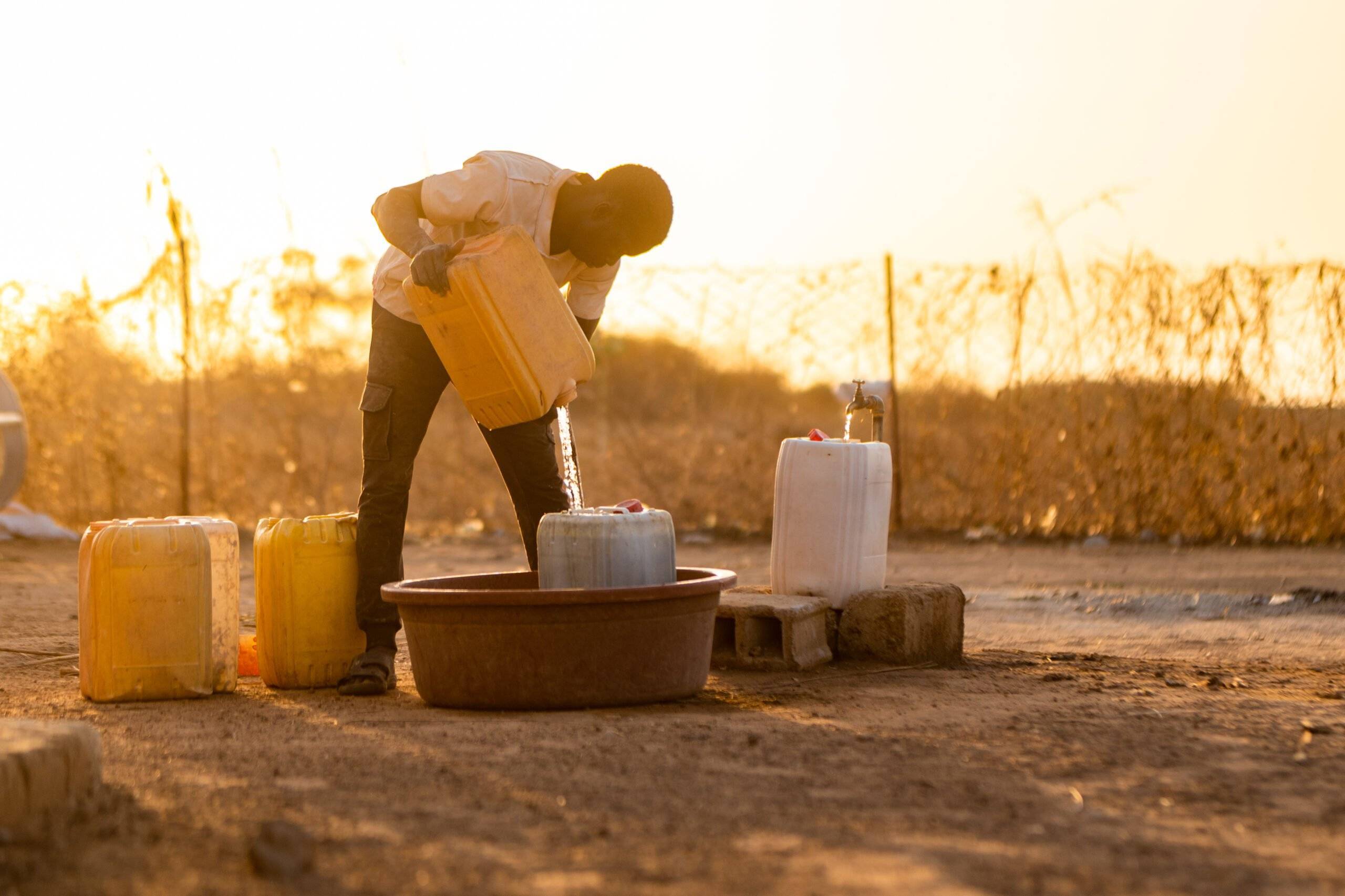 A man pouring water into a jug in Senegal West Africa.