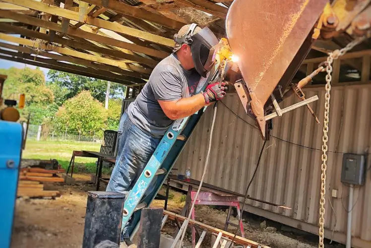 Banner image of a Andy Bachert , COO of Friends In Action Intl., welding on a multi-trade construction project.