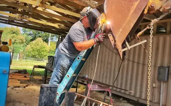 Banner image of a Andy Bachert , COO of Friends In Action Intl., welding on a multi-trade construction project.