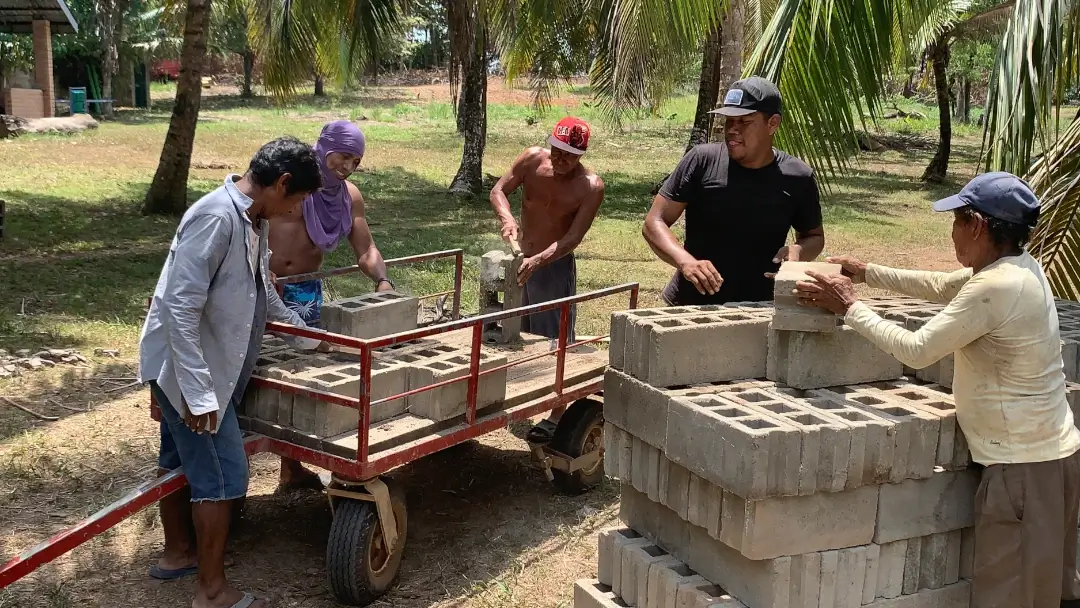 A group of Rama men working together to move bricks for construction.