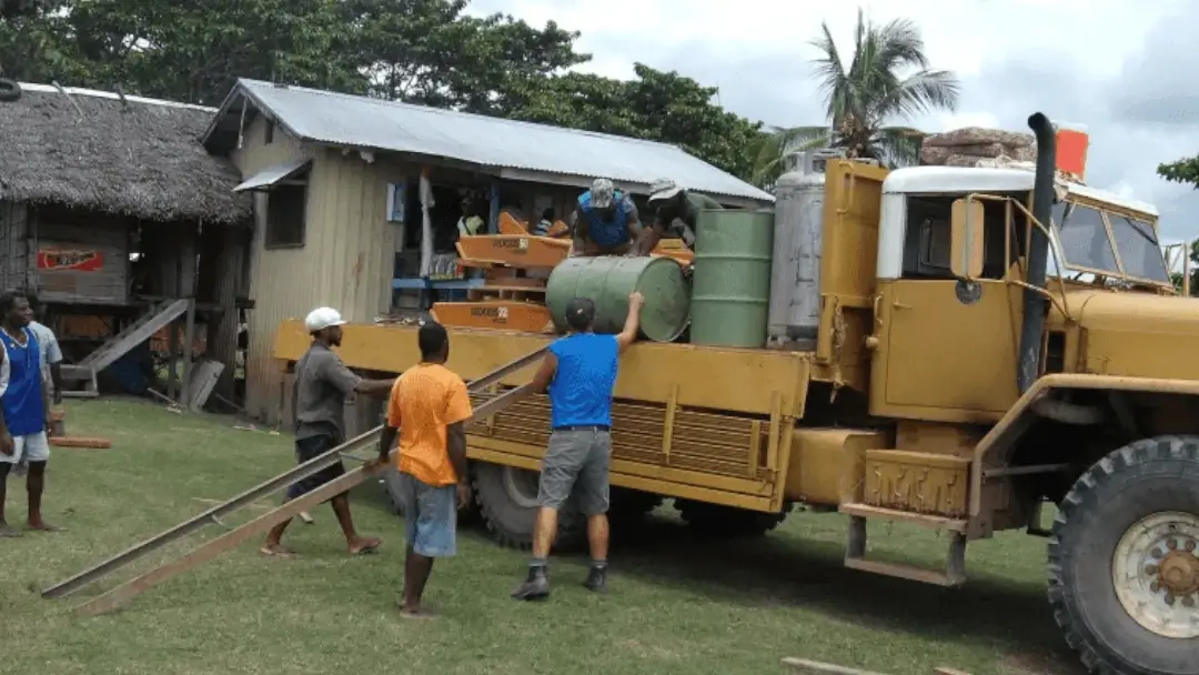 Light-of-Truth Friends In Action Intl. members and natives working on loading barrels onto a construction vehicle.