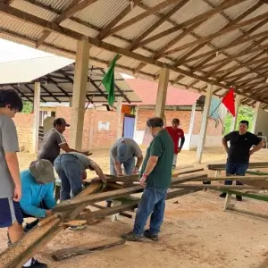 Friends In Action International volunteers and people of Bolivia working on wooden construction frame.
