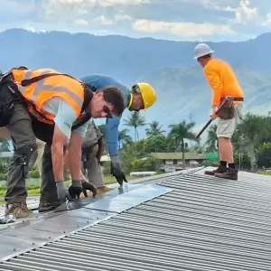 Friends In Action International volunteers helping install solar paneling.