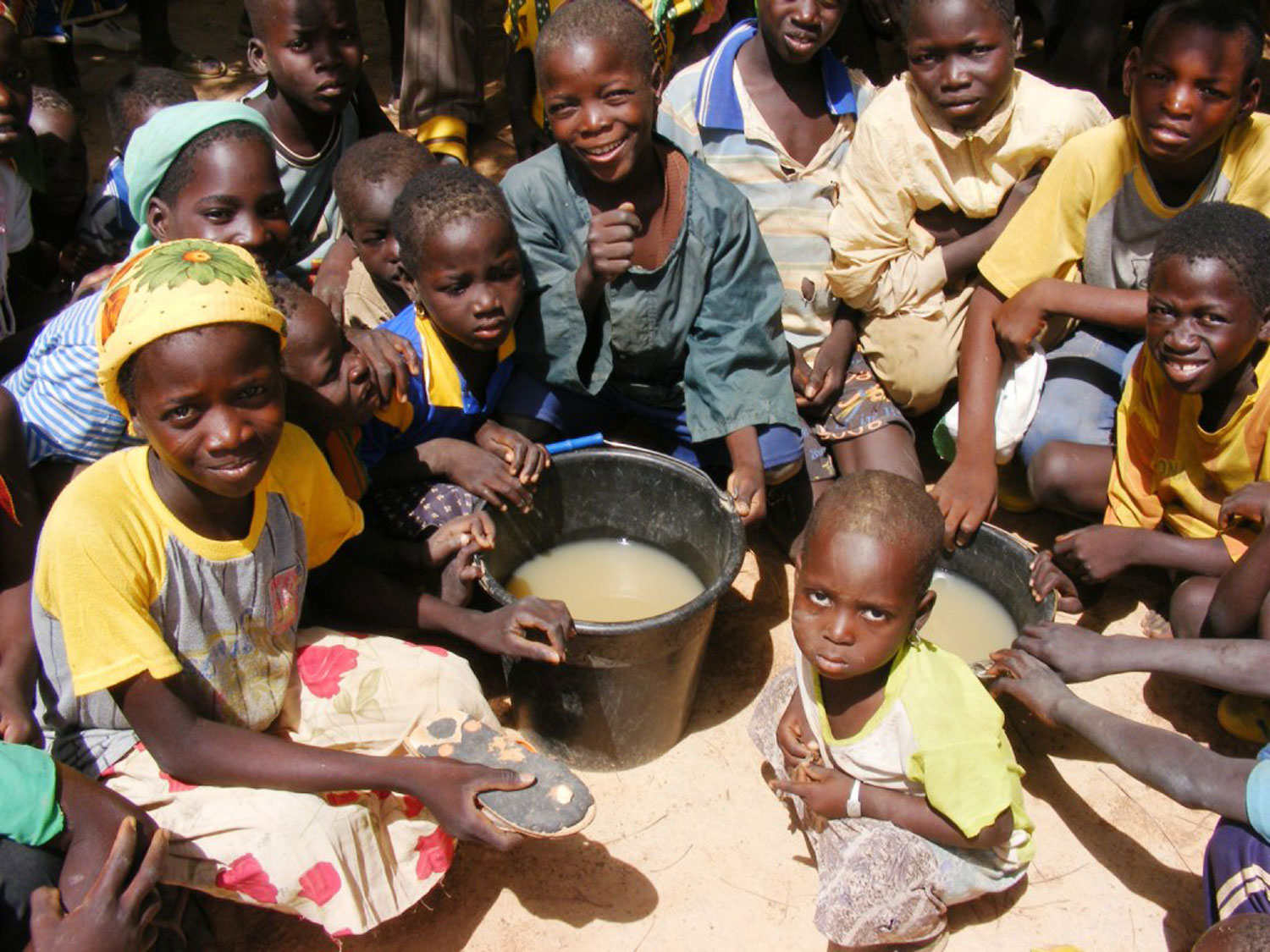 A group of children surrounding a bucket of unclean water in west africa